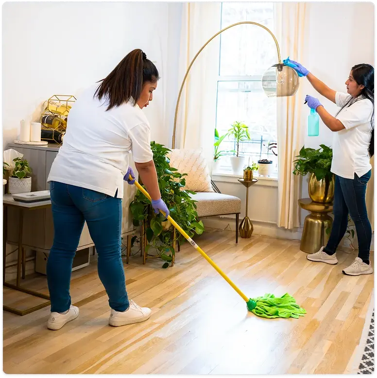 Cleaner mopping a wooden floor near a large arched mirror in a cozy living room